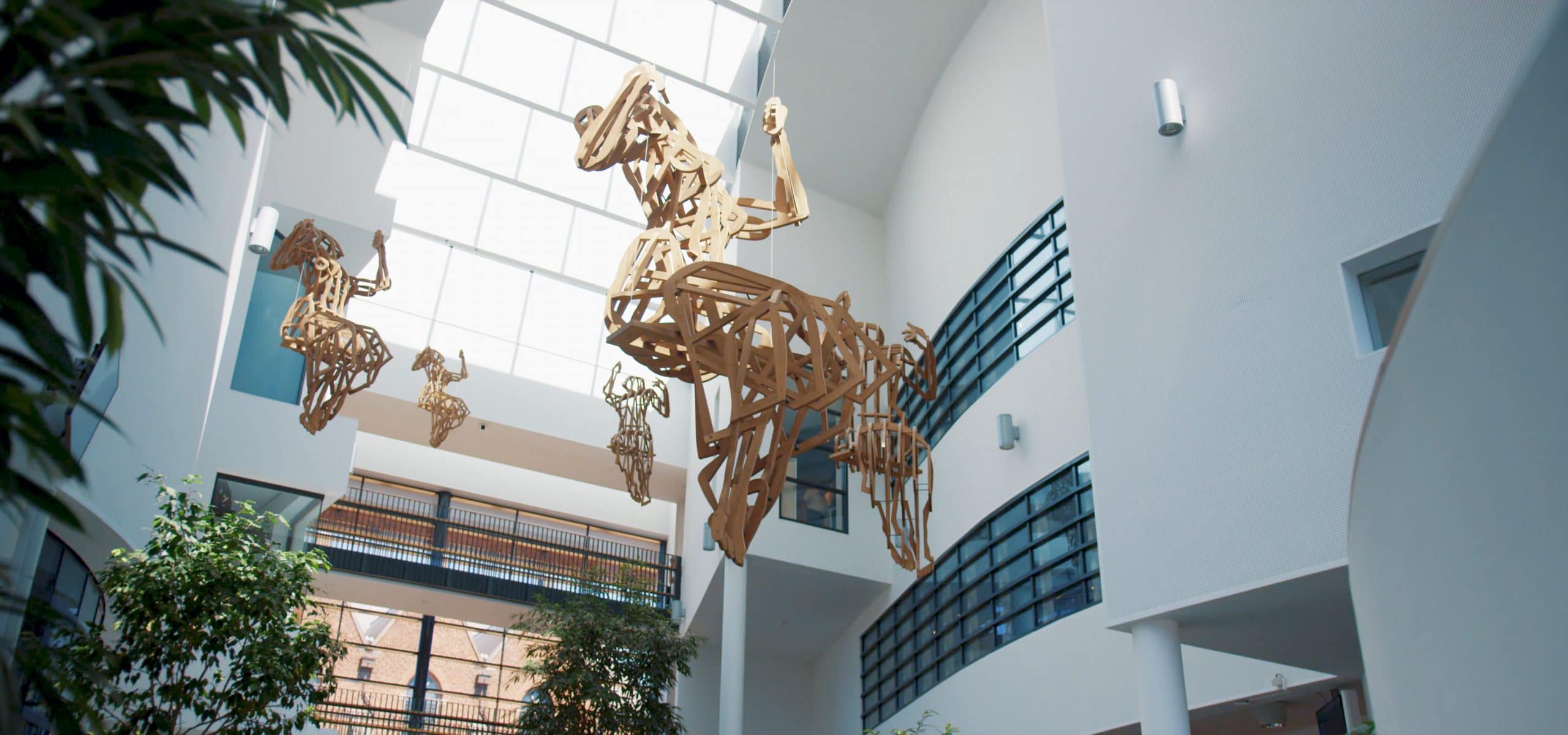 Foto van de houten beelden, 'de schommelende meisjes', in de hal van het gemeentehuis in Rijssen.